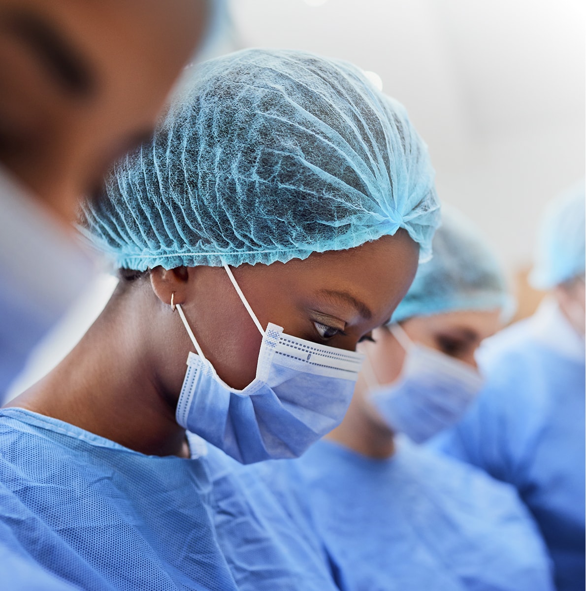 Medical professionals in surgical attire and masks.